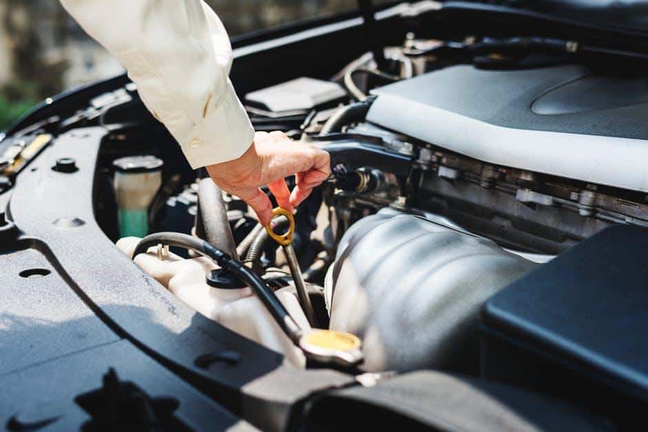 Person Touching Gray Metal Rod on Vehicle Engine